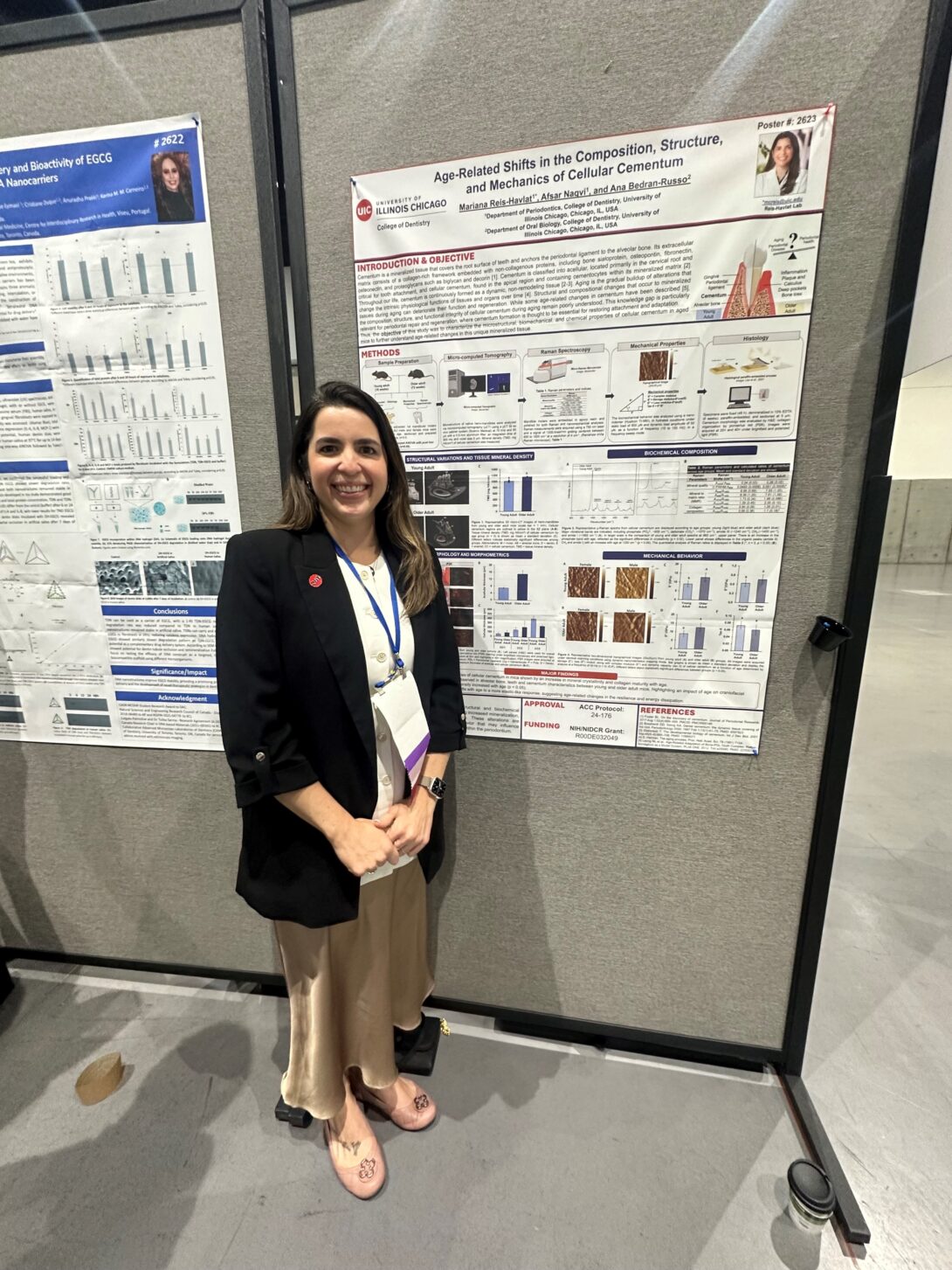Dr. Mariana Reis-Havlat stands smiling in front of two scientific posters on display boards. The poster beside her is titled about cellular cementum, indicating research findings at the AADOCR- IADR 2026 meeting.